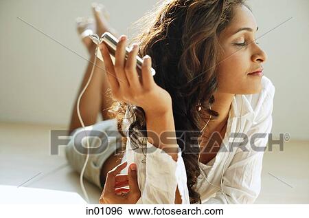 Woman lying on front, listening to music from MP3 player View Large Photo Image Stock Photograph - Woman lying on front, listening to music from MP3 player. Fotosearch