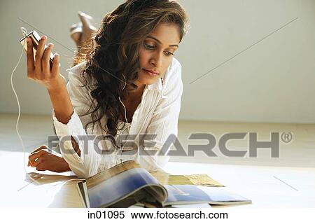 Woman lying on front, listening to music from MP3 player View Large Photo Image Stock Photography - Woman lying on front, listening to music from MP3 player. Fotosearch