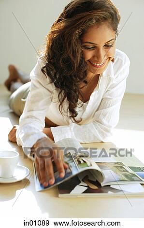 Woman lying on front, looking at magazine, smiling View Large Photo Image Stock Photo - Woman lying on front, looking at magazine, smiling. Fotosearch
