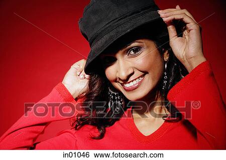 Woman smiling at camera, adjusting hat on head View Large Photo Image Stock Photograph - Woman smiling at camera, adjusting hat on head. Fotosearch