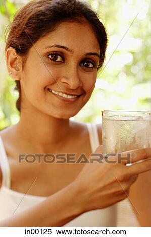 Woman smiling at camera, holding glass of water View Large Photo Image Stock Photography - Woman smiling at camera, holding glass of water. Fotosearch