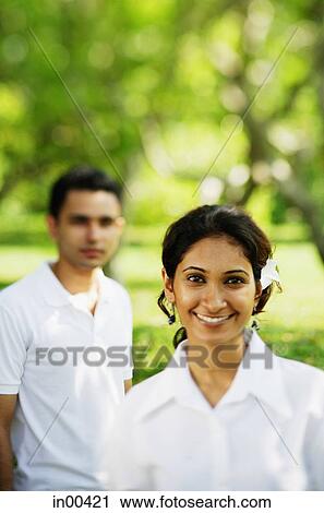 Stock Image - Woman smiling at camera, man in the background. Fotosearch