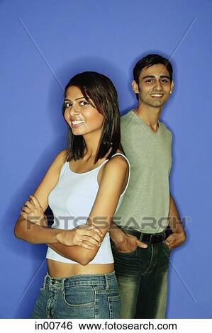 Woman standing in front of man, arms crossed, man behind with hands in pocket View Large Photo Image Stock Photograph - Woman standing in front of man, arms crossed, man behind with hands in pocket. Fotosearch