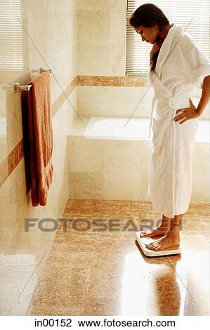 Stock Image - Woman standing on weight scale. Fotosearch