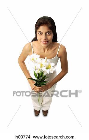 Picture - Woman standing with flowers, looking at camera. Fotosearch