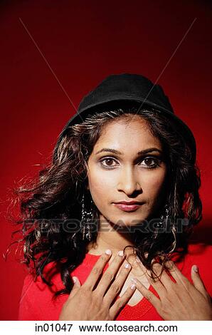 Stock Photo - Woman wearing hat, looking at camera, hands on chest. Fotosearch
