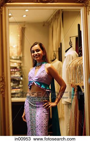 Woman wearing sari, looking at reflection in mirror, hand on hip View Large Photo Image Stock Image - Woman wearing sari, looking at reflection in mirror, hand on hip. Fotosearch