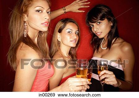 Stock Photo - Women looking at camera, holding drinks, portrait. Fotosearch