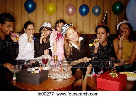 Stock Photo - Young adults celebrating birthday, wearing party hats. Fotosearch
