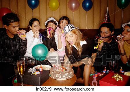 Stock Photo - Young adults celebrating birthday with noisemakers and party hats. Fotosearch