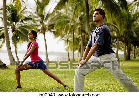 Stock Image - Young adults doing exercises in park.. Fotosearch