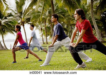 Stock Image - Young adults doing exercises in park.. Fotosearch