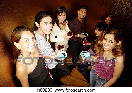 Stock Photo - Young adults holding drinks, looking at camera. Fotosearch