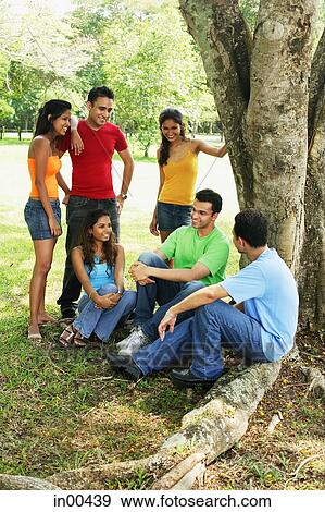 Young adults, sitting and standing in park, talking View Large Photo Image Stock Photo - Young adults, sitting and standing in park, talking. Fotosearch