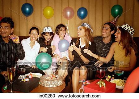 Stock Image - Young adults sitting side by side, celebrating. Fotosearch
