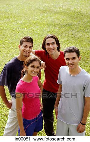 Young adults standing together, looking at camera, smiling View Large Photo Image Stock Image - Young adults standing together, looking at camera, smiling. Fotosearch