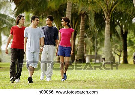 Young adults walking in park, side by side View Large Photo Image Stock Photograph - Young adults walking in park, side by side. Fotosearch