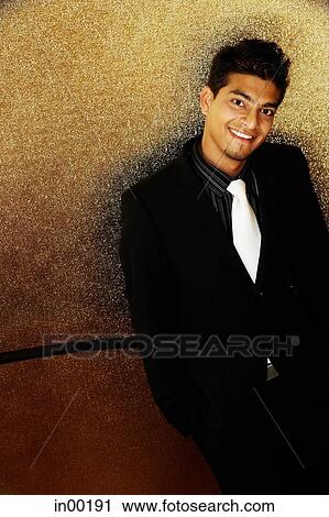 Stock Image - Young man dressed in suit, looking up at camera. Fotosearch