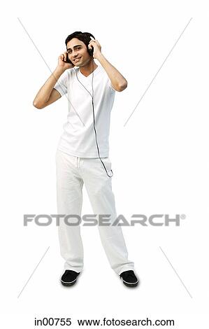Young man listening to headphones, smiling at camera View Large Photo Image Stock Photography - Young man listening to headphones, smiling at camera. Fotosearch