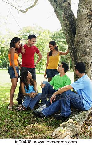 Young men and women, sitting and standing in park, talking View Large Photo Image Stock Photo - Young men and women, sitting and standing in park, talking. Fotosearch