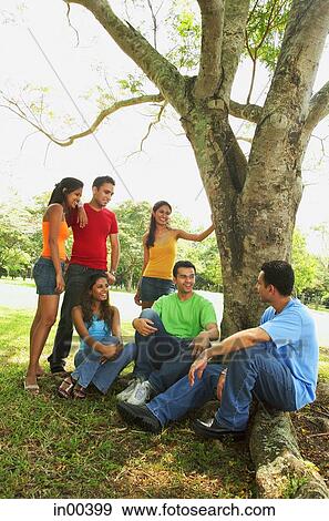 Young men and women, sitting in park, talking View Large Photo Image Stock Photo - Young men and women, sitting in park, talking. Fotosearch