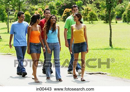Young men and women walking in park View Large Photo Image Stock Image - Young men and women walking in park. Fotosearch