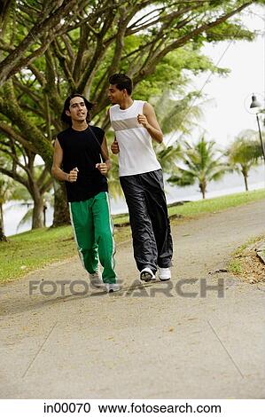 Stock Image - Young men jogging in park. Fotosearch