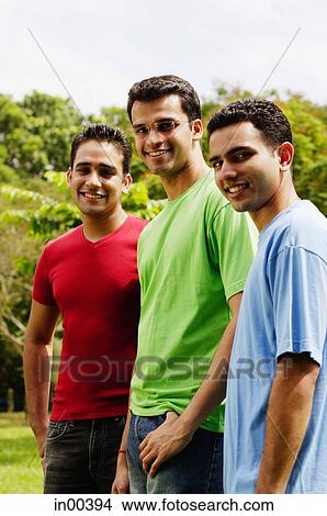 Young men standing side by side, looking at camera View Large Photo Image Picture - Young men standing side by side, looking at camera. Fotosearch