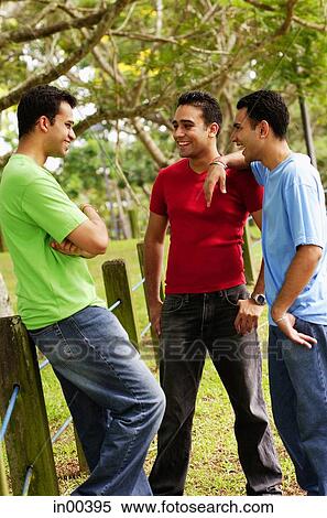 Young men standing, talking View Large Photo Image Stock Photography - Young men standing, talking. Fotosearch