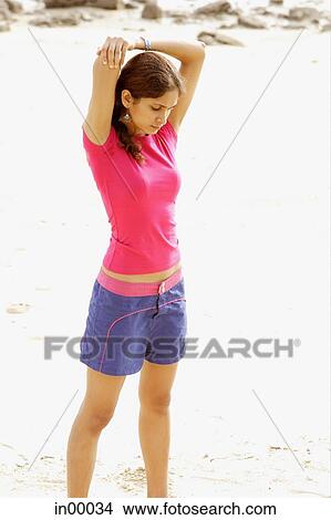 Picture - Young woman at the beach, stretching, arms behind her head. Fotosearch