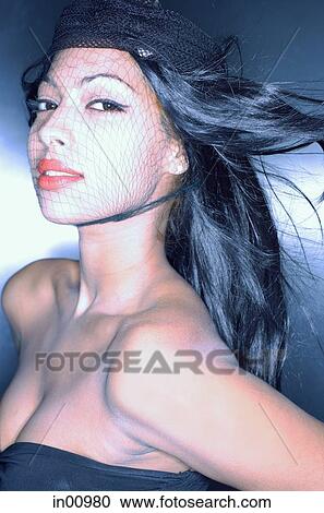Stock Image - Young woman, fishnet covering face, head shot. Fotosearch