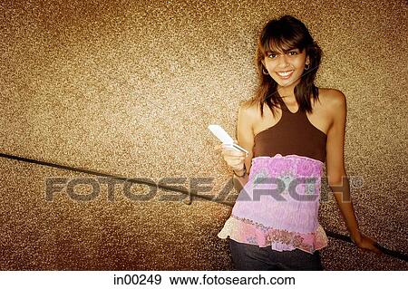 Young woman holding mobile phone, smiling View Large Photo Image Stock Photo - Young woman holding mobile phone, smiling. Fotosearch