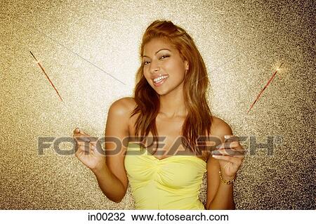 Young woman holding sparklers, looking at camera, portrait View Large Photo Image Stock Image - Young woman holding sparklers, looking at camera, portrait. Fotosearch
