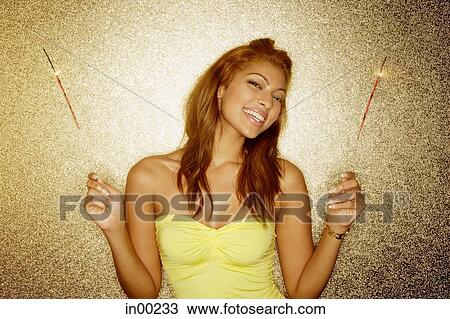 Young woman holding sparklers, smiling at camera, portrait View Large Photo Image Stock Image - Young woman holding sparklers, smiling at camera, portrait. Fotosearch