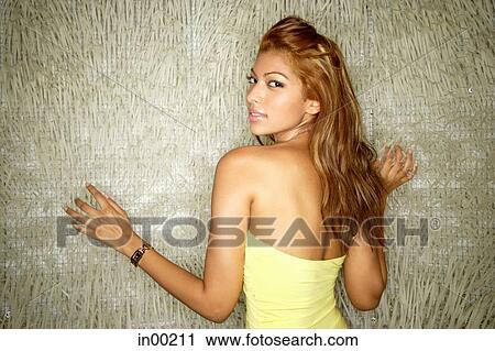 Stock Image - Young woman in tube top, looking at camera over shoulder. Fotosearch