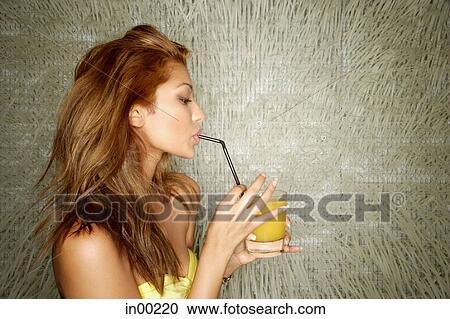 Stock Image - Young woman sipping drink with straw. Fotosearch