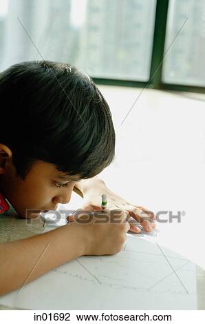 Stock Image - Boy lying on floor, drawing with crayons. Fotosearch