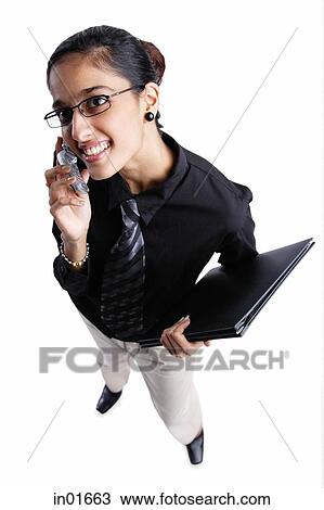 Stock Image - Business woman using mobile phone, high angle view. Fotosearch