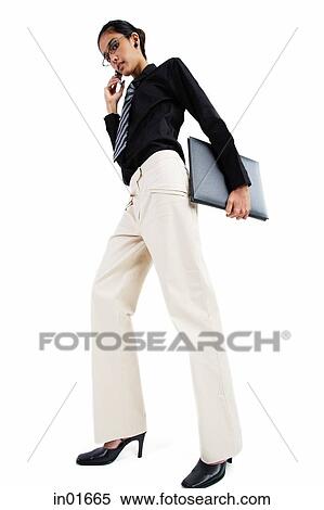 Stock Photography - Business woman using mobile phone, carrying folder, looking at camera, low angle view. Fotosearch