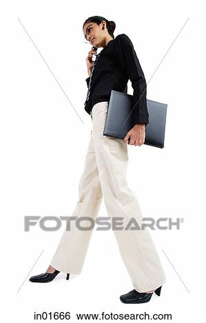 Business woman with mobile phone, carrying folder, low angle view View Large Photo Image Stock Photograph - Business woman with mobile phone, carrying folder, low angle view. Fotosearch