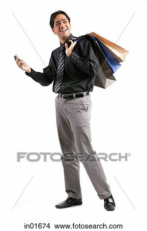 Picture - Businessman carrying shopping bags over shoulder, holding mobile phone. Fotosearch