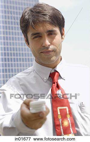 Businessman holding mobile phone towards camera View Large Photo Image Stock Photo - Businessman holding mobile phone towards camera. Fotosearch