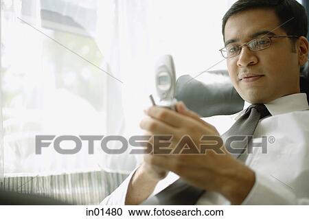 Stock Image - Businessman looking at mobile phone. Fotosearch