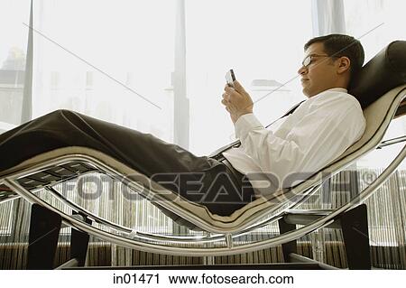 Businessman reclining on chair, using PDA View Large Photo Image Stock Image - Businessman reclining on chair, using PDA. Fotosearch
