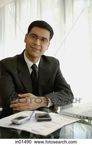 Businessman sitting at desk with laptop, PDA and mobile phone, looking at camera View Large Photo Image Stock Image - Businessman sitting at desk with laptop, PDA and mobile phone, looking at camera. Fotosearch