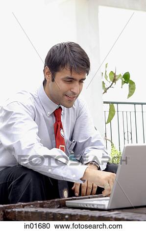 Businessman sitting in patio, using laptop View Large Photo Image Stock Image - Businessman sitting in patio, using laptop. Fotosearch