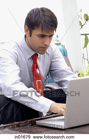 Businessman sitting outdoors, using laptop View Large Photo Image Stock Photo - Businessman sitting outdoors, using laptop. Fotosearch