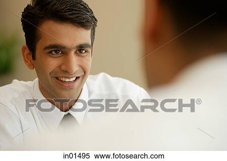Stock Photography - Businessman smiling at person in front of him. Fotosearch