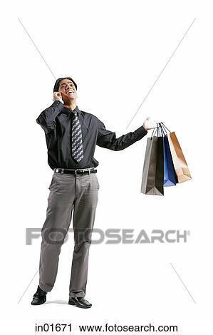 Stock Image - Businessman talking on mobile phone, carrying shopping bags. Fotosearch