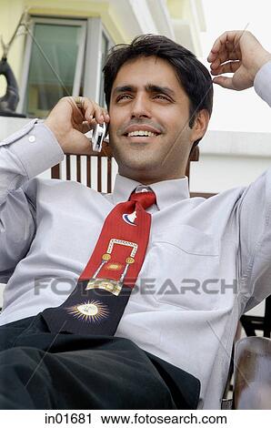 Stock Image - Businessman using mobile phone, smiling. Fotosearch